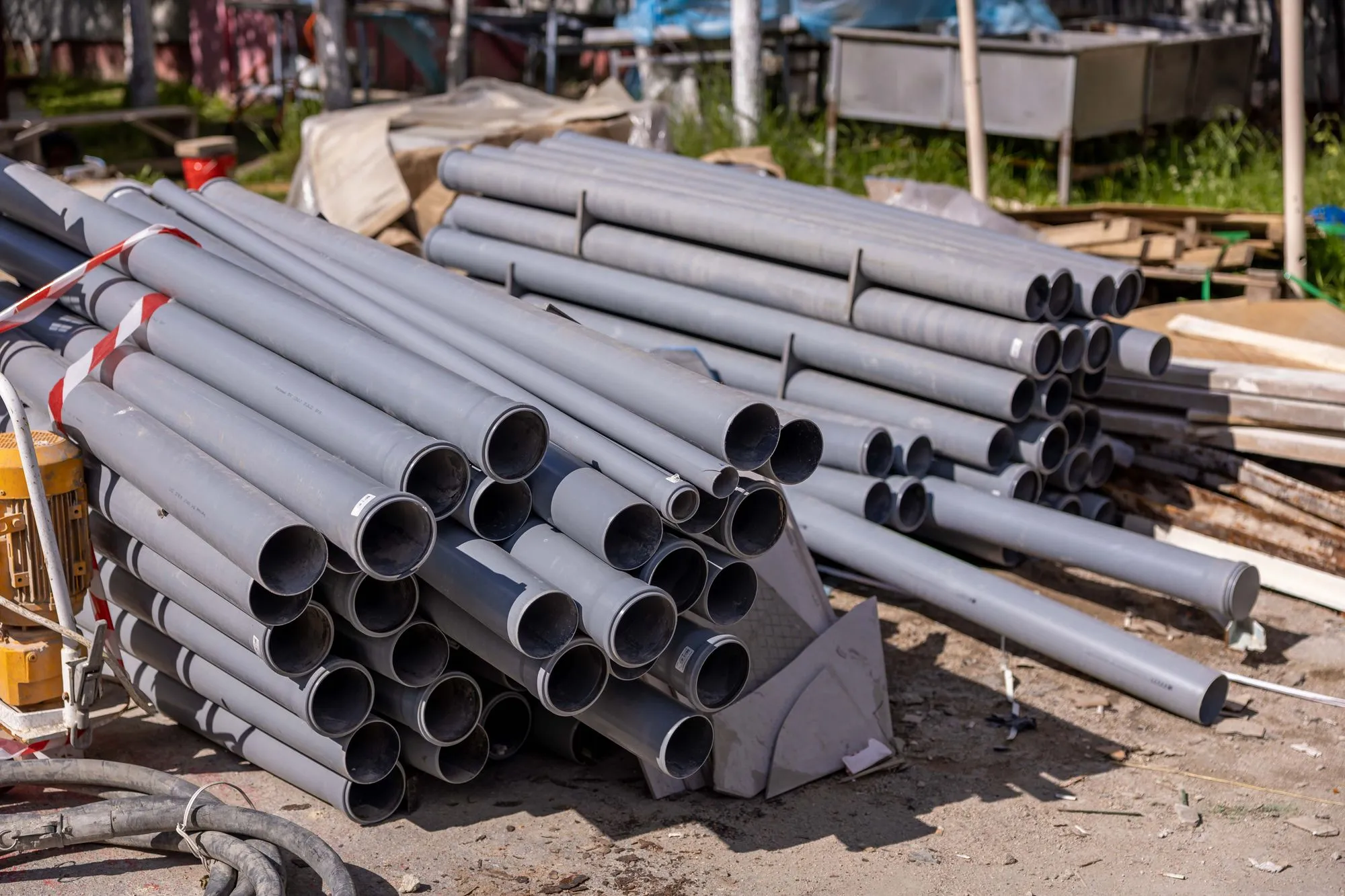 Stack of gray PVC conduit pipe at a construction site