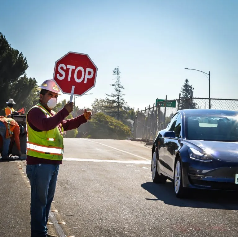 Hudson Excavation flagger in safety gear directing traffic with a stop sign on a road job
